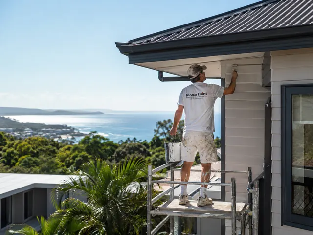 Generated house painter working from scaffolding above a coastal view